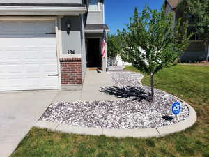 Entrance to property with a yard, brick siding, stucco siding, and an attached garage