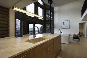 Kitchen with a sink, high vaulted ceiling, light wood finished floors, light countertops, and rustic walls