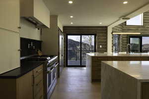 Kitchen featuring light wood finished floors, rustic walls, a sink, custom range hood, and high end appliances