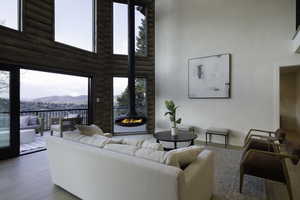 Living room with a mountain view, log walls, a towering ceiling, wood finished floors, and a wood stove