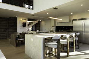 Kitchen with a large island, a kitchen bar, stainless steel built in fridge, and light wood-style flooring