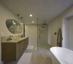 Full bathroom featuring double vanity, a freestanding bath, a walk in shower, and a sink
