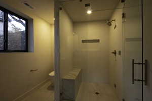 Full bathroom featuring toilet, tile patterned flooring, visible vents, and a shower stall