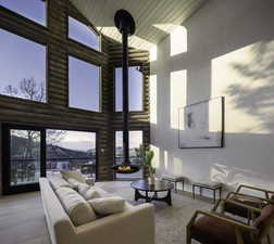Living area with a wood stove, log walls, high vaulted ceiling, and wooden ceiling