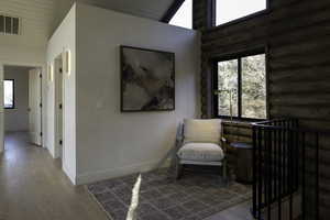 Sitting room featuring wood-type flooring, baseboards, rustic walls, and plenty of natural light