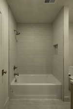 Bathroom with tile patterned flooring, shower / tub combination, visible vents, and vanity