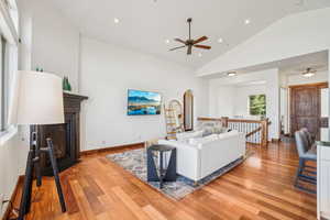 Living area featuring light wood finished floors, a fireplace with flush hearth, arched walkways, ceiling fan, and recessed lighting