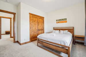 Bedroom with light colored carpet, baseboards, and a closet