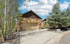Exterior space featuring stone siding, board and batten siding, an attached garage, and concrete driveway