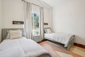 Bedroom featuring baseboards, wood finished floors, and lofted ceiling