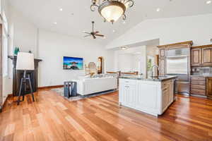 Kitchen featuring a sink, stainless steel built in refrigerator, light wood finished floors, ceiling fan, and open floor plan
