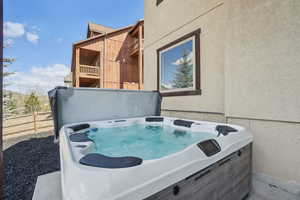 Exterior space with a hot tub, fence, and stucco siding