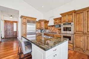 Kitchen with high vaulted ceiling, a sink, dark wood finished floors, backsplash, and appliances with stainless steel finishes