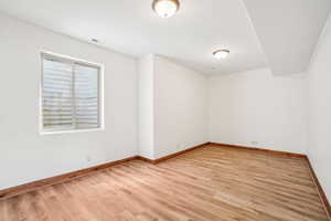 Unfurnished room featuring baseboards, visible vents, and light wood-style floors