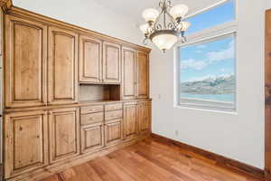 Unfurnished dining area featuring plenty of natural light, light wood-type flooring, a chandelier, and baseboards