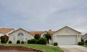 Mediterranean / spanish home featuring stucco siding, a front yard, a chimney, concrete driveway, and a tiled roof
