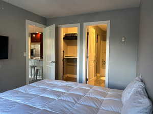 Bedroom with a closet, ensuite bath, stainless steel fridge, and a spacious closet