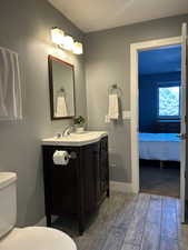 Half bath with toilet, wood finished floors, and vanity