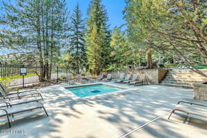 View of pool with stairway, fence, a patio, and a hot tub