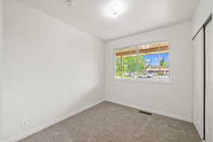 Unfurnished bedroom featuring carpet floors, baseboards, visible vents, and a closet