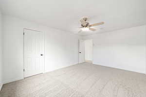 Spare room with a ceiling fan, light carpet, and baseboards