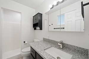 Bathroom with vanity, toilet, and a tile shower