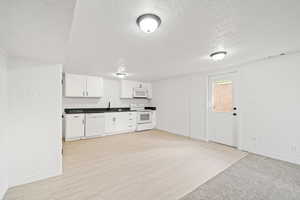 Kitchen with a textured ceiling, white appliances, and baseboards