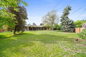 View of yard featuring fence and a sunroom