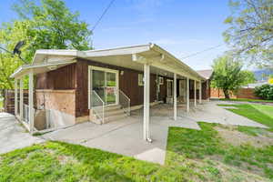 View of front of property with a patio area, entry steps, fence, and brick siding