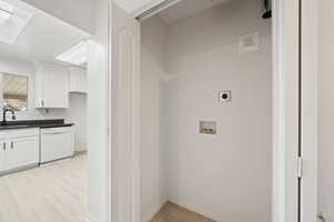 Clothes washing area featuring a sink, laundry area, hookup for an electric dryer, light wood finished floors, and hookup for a washing machine