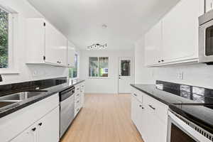 Kitchen featuring light wood finished floors, white cabinets, plenty of natural light, and appliances with stainless steel finishes