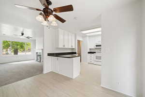Kitchen featuring light wood finished floors, ceiling fan, open floor plan, and white appliances