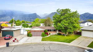 Ranch-style home featuring a mountain view, a garage, fence, a front lawn, and concrete driveway