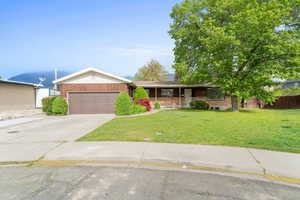 Ranch-style house with a front lawn, driveway, covered porch, and a garage
