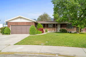 Ranch-style house with a porch, brick siding, driveway, a garage, and a front lawn