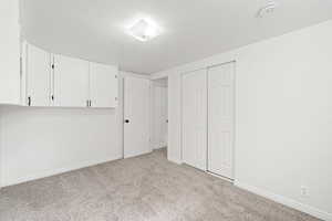 Unfurnished bedroom with light colored carpet, a closet, and baseboards