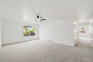 Spare room with carpet flooring, baseboards, a ceiling fan, and visible vents