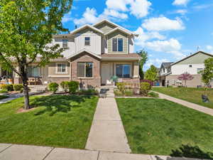 Craftsman-style house with a front yard, a porch, brick siding, and board and batten siding