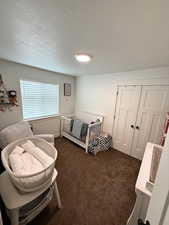 Bedroom featuring dark colored carpet, a textured ceiling, and a closet