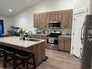 Kitchen featuring lofted ceiling, a breakfast bar, recessed lighting, a sink, and appliances with stainless steel finishes