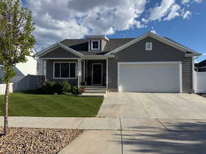 Craftsman inspired home featuring a garage, fence, a front yard, roof with shingles, and driveway