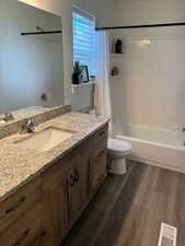 Bathroom with visible vents, vanity, shower / bath combo with shower curtain, wood finished floors, and toilet