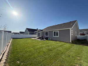 Rear view of house with a lawn, a fenced backyard, and a patio area