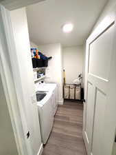Clothes washing area featuring laundry area, light wood-style flooring, and washing machine and clothes dryer