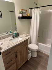 Full bathroom with vanity, shower / tub combo, wood finished floors, and toilet