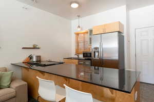 Kitchen featuring a sink, a peninsula, stainless steel appliances, a breakfast bar, and hanging light fixtures