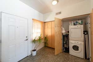 Laundry area with laundry area, stacked washer and clothes dryer, carpet, and visible vents