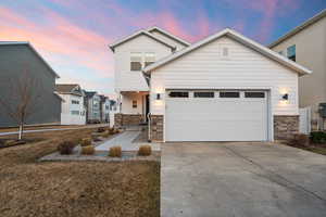 View of front facade featuring stone siding, concrete driveway, and an attached garage