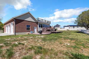 Back of house with a lawn, brick siding, fence, a garage, and concrete driveway