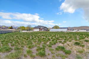 View of yard with an attached garage, a mountain view, and fence